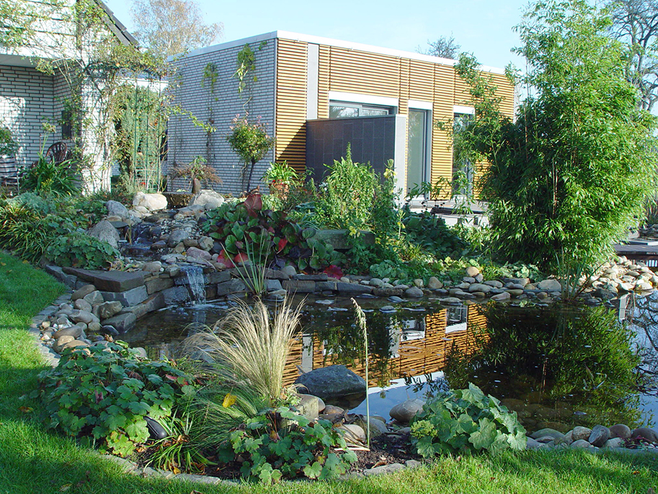 Gartenteich in einem Garten mit Höhenunterschieden unf robusten Pflanzen.