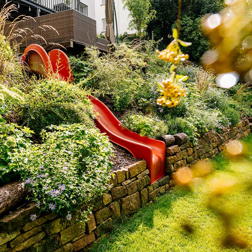In einem Garten ist eine Rutsche kreativ integriert
