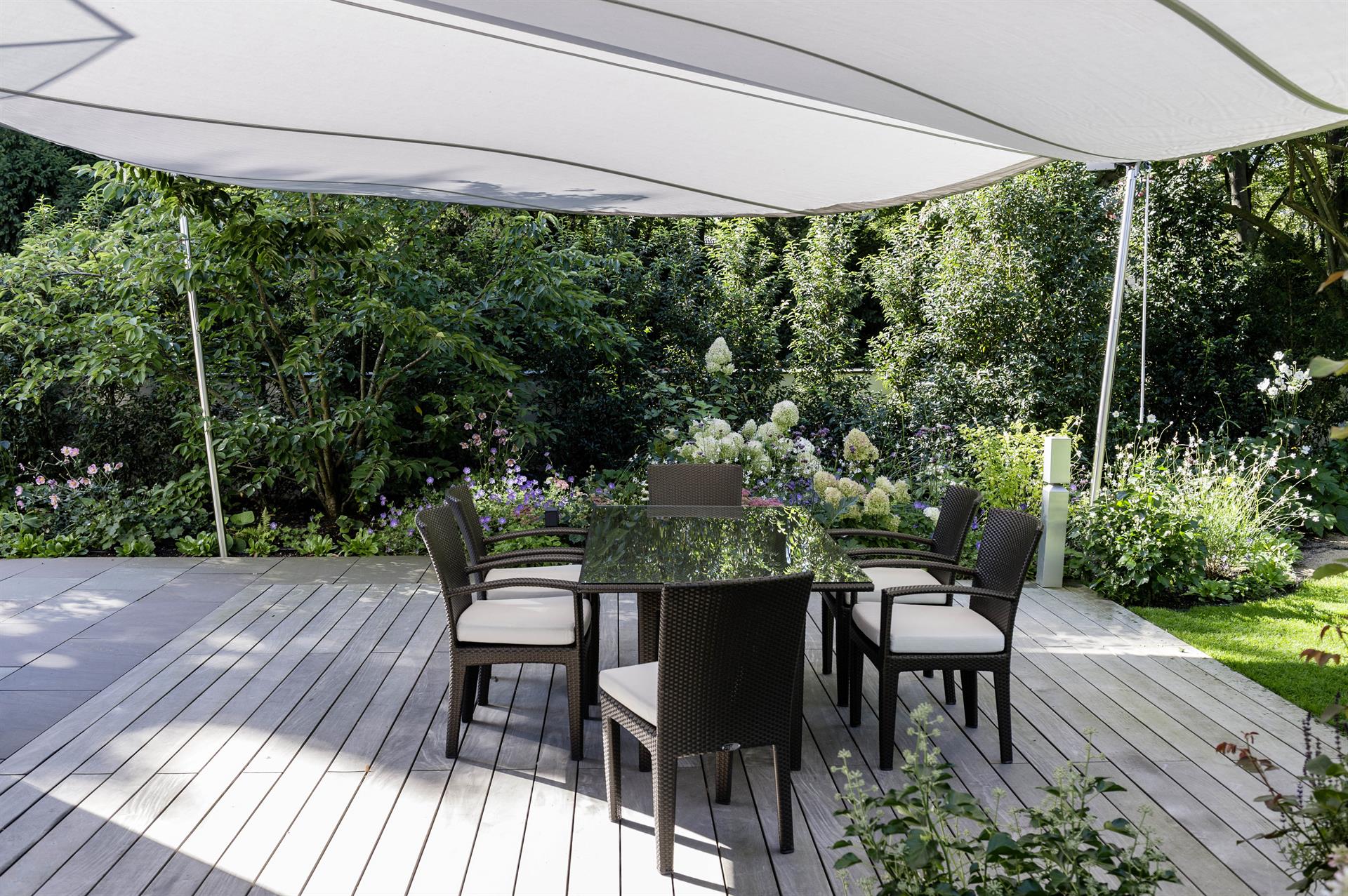 Holzterrasse im Garten mit Sonnenschutz und Esstisch