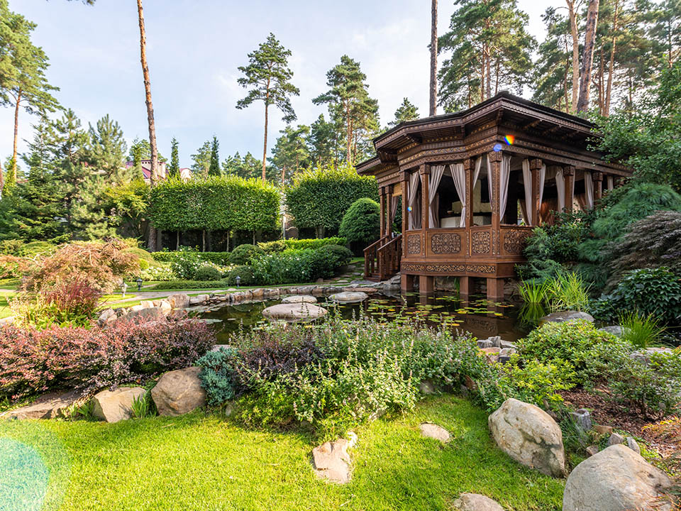 Holz-Pavillon im asiatischen Garten mit Teich, Natursteinen und Stauden