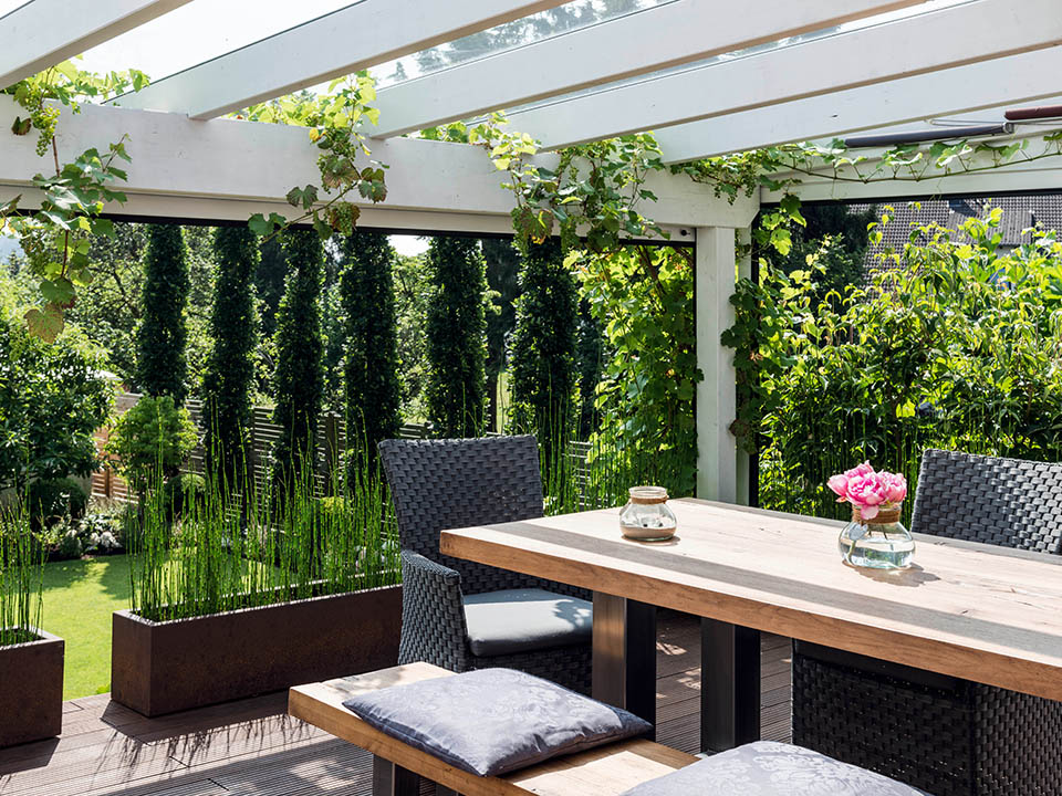 Pergola mit Holtz- und Glasdach und Steinsäulen als Halterung mit gemütlichen Sitzplätzen
